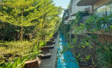 Poolside relaxation at Maya Sanur Resort surrounded by greenery and tranquility