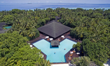 Aerial view of Adaaran Meedhupparu resort surrounded by lush greenery and ocean