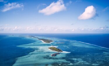 Aerial view of Jawakara Dheru Island surrounded by vibrant blue ocean waters