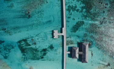 Aerial view of Jawakara Dheru Island villas surrounded by turquoise waters and coral reefs