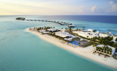 Aerial view of Riu Atoll resort with overwater villas and sandy beach