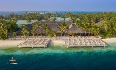 Aerial view of Vilamendhoo beach resort with rows of sun loungers by the ocean and lush greenery