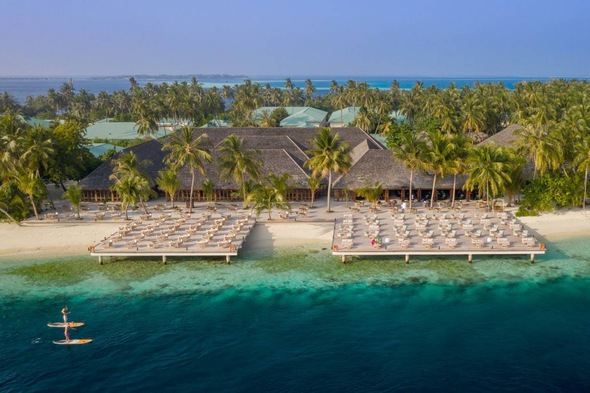 Aerial view of Vilamendhoo beach resort with rows of sun loungers by the ocean and lush greenery