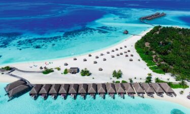 Aerial view of overwater bungalows at Constance Moofushi surrounded by turquoise waters and white sand beach