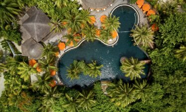 Aerial view of the Sun Siyam Iru Fushi pool area surrounded by dense tropical vegetation and vibrant palm trees