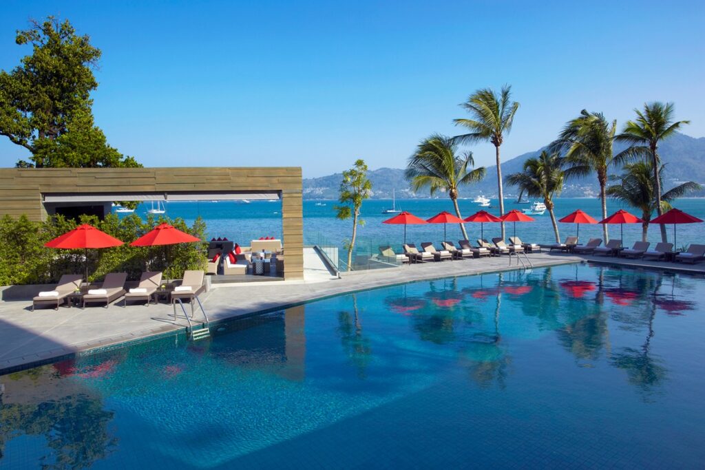 Amari Phuket poolside area with red umbrellas and a view of the ocean