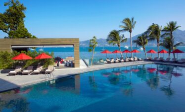 Amari Phuket poolside area with red umbrellas and a view of the ocean