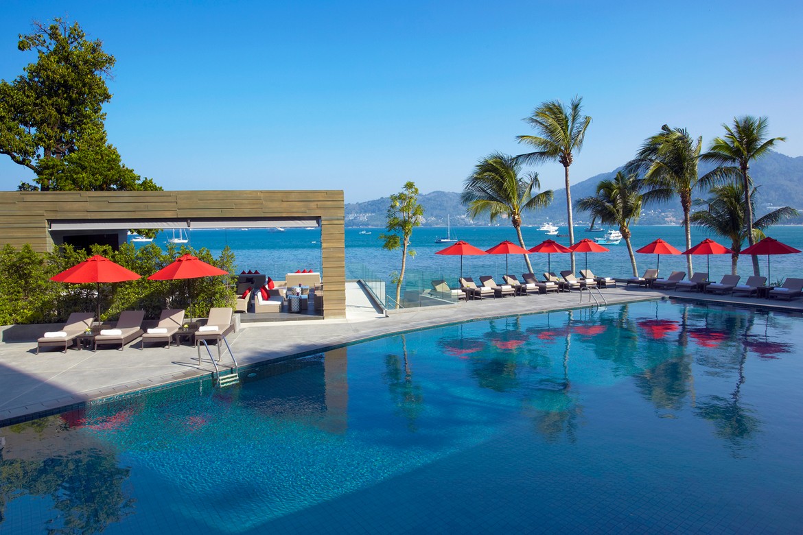 Amari Phuket poolside area with red umbrellas and a view of the ocean