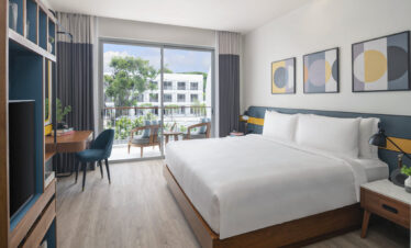 Bright and airy bedroom at Avani Chaweng Samui with a view of the resort’s garden and modern furnishings