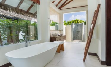 Bright bathroom at Heritance Aarah with a freestanding tub and outdoor shower