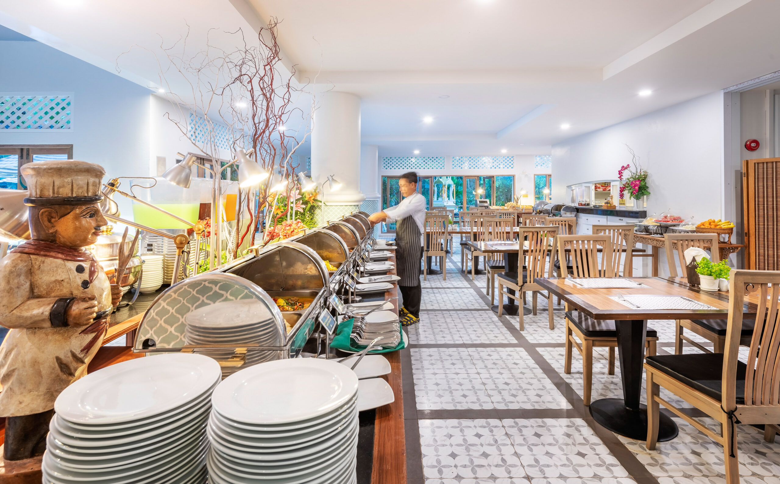 Buffet station at Chada Thai Village with a chef preparing dishes and a row of serving trays