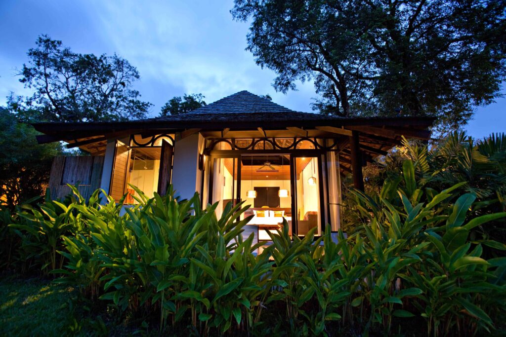 Bungalow surrounded by lush tropical plants at The Vijitt Resort in the evening