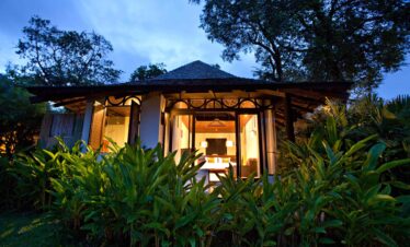 Bungalow surrounded by lush tropical plants at The Vijitt Resort in the evening
