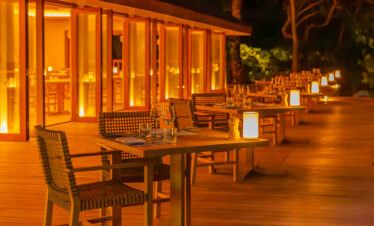 Candlelit outdoor dining area at Meeru Island Resort with warm amber lighting creating a cozy atmosphere at night