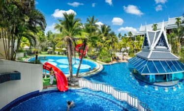 Chada Thai Village pool area with water slides and lush tropical surroundings on a sunny day