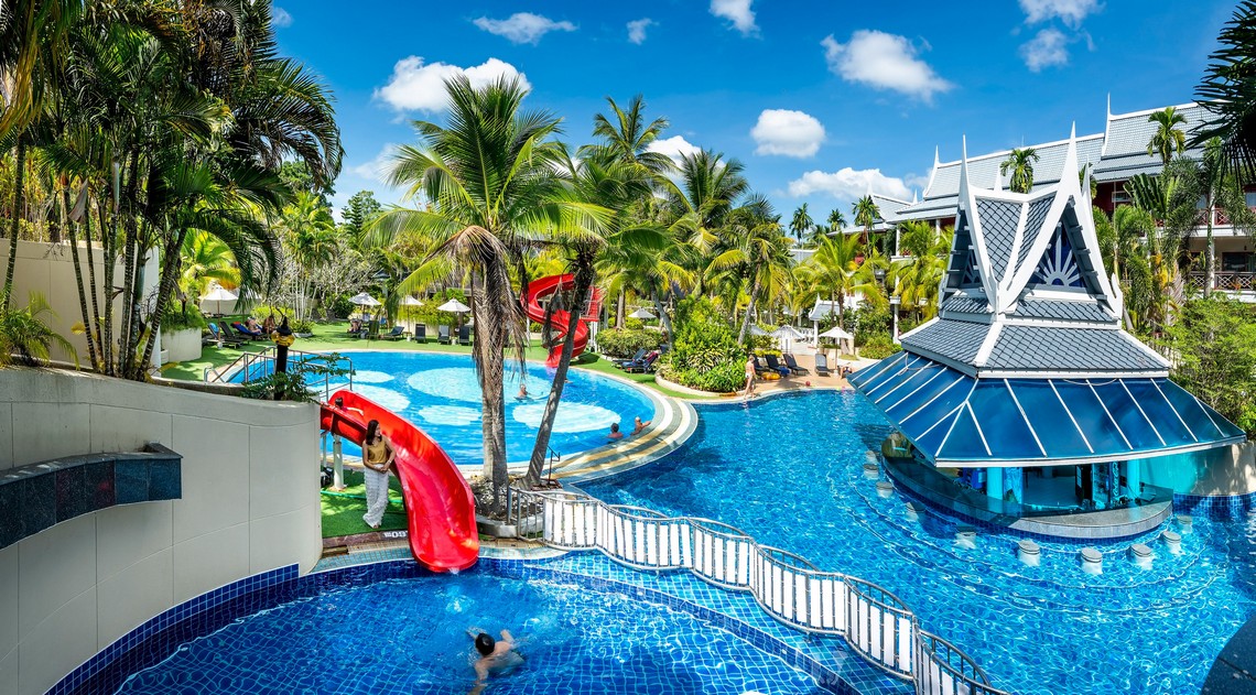 Chada Thai Village pool area with water slides and lush tropical surroundings on a sunny day