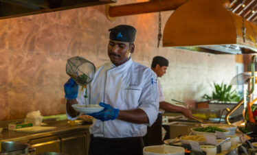Chef preparing a dish in the open kitchen at Vilamendhoo offering a delightful culinary experience for guests