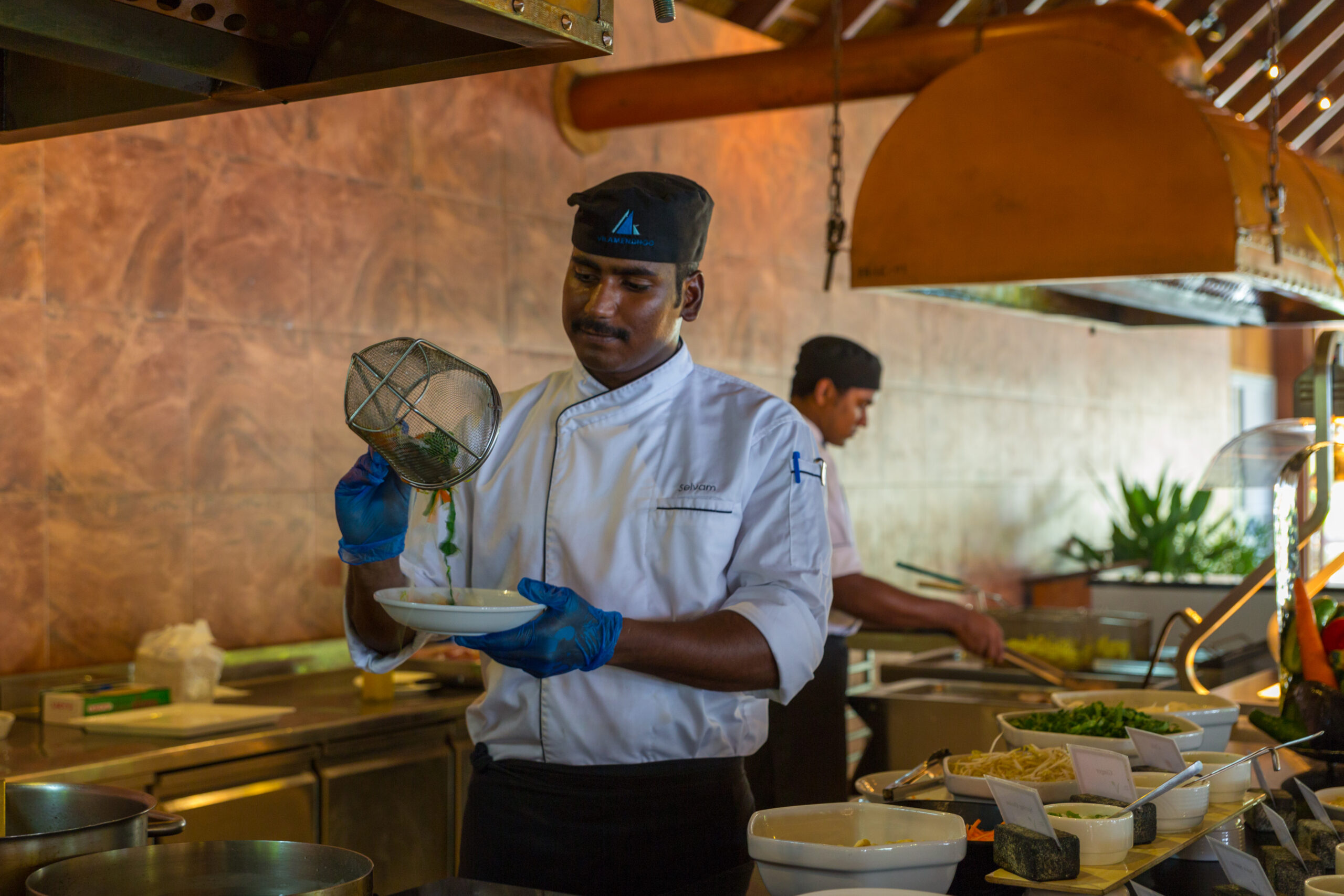Chef preparing a dish in the open kitchen at Vilamendhoo offering a delightful culinary experience for guests