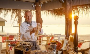Chef preparing fresh pasta at You and Me by Cocoon resort with a sunset view