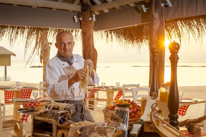 Chef preparing fresh pasta at You and Me by Cocoon resort with a sunset view