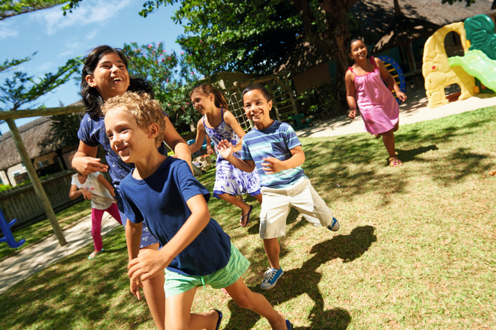 Children playing on the grassy area of the kids club at Constance Belle Mare Plage
