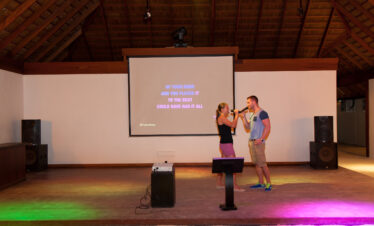 Couple singing karaoke on stage at Vilamendhoo creating fun memories during their stay