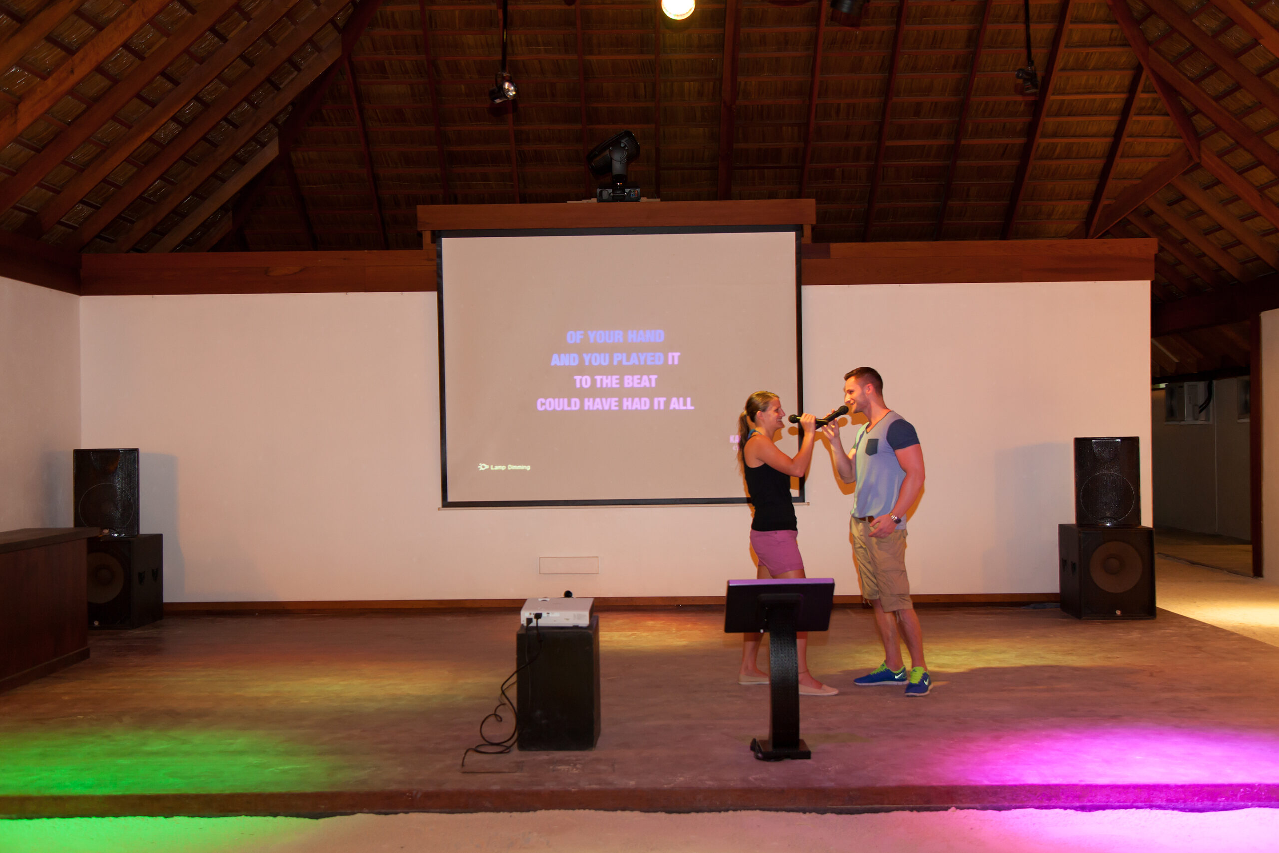 Couple singing karaoke on stage at Vilamendhoo creating fun memories during their stay