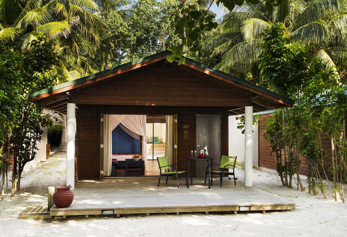 Cozy beach villa at Meeru Island Resort with a private terrace surrounded by tropical greenery and a sandy path