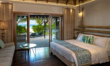 Cozy bedroom in a beach villa at Constance Moofushi with an ocean view and direct beach access