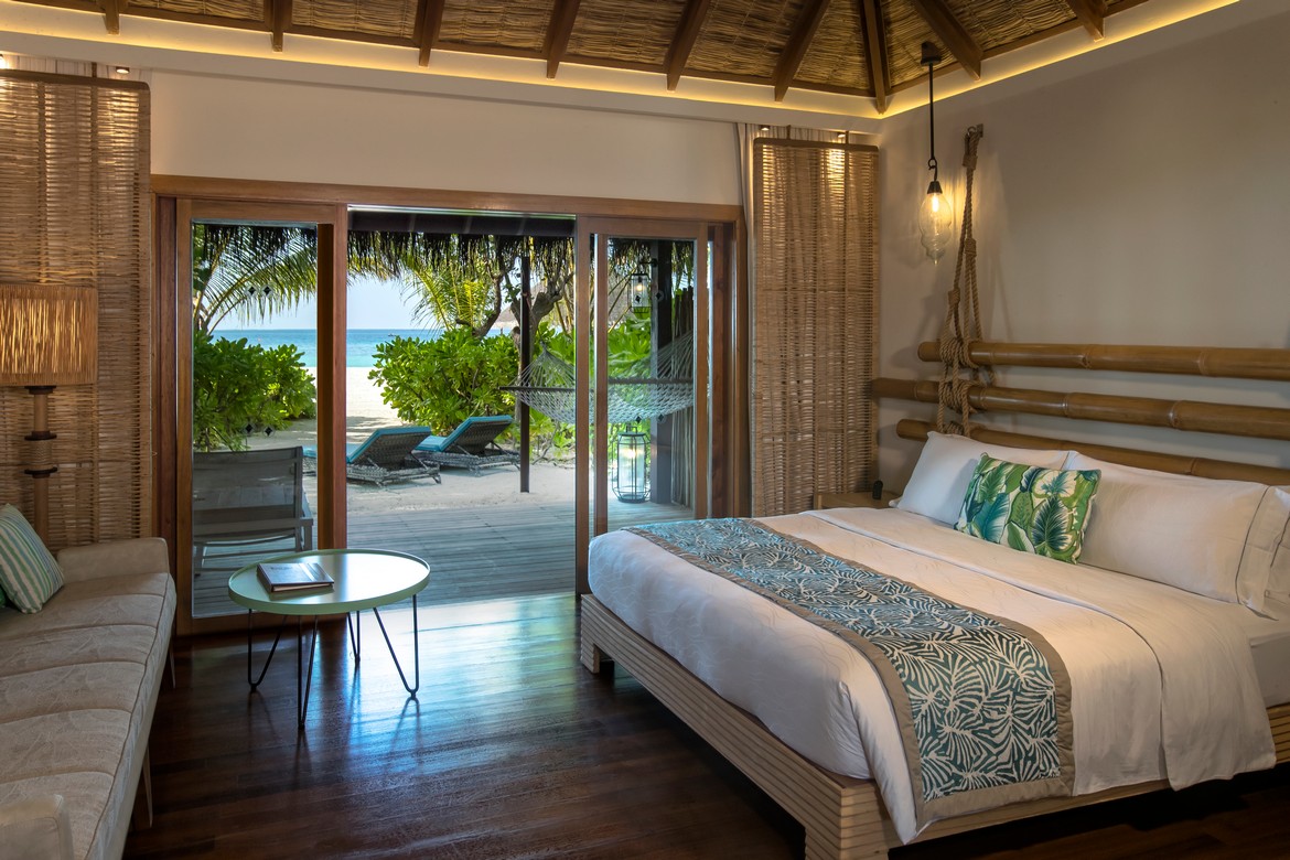 Cozy bedroom in a beach villa at Constance Moofushi with an ocean view and direct beach access