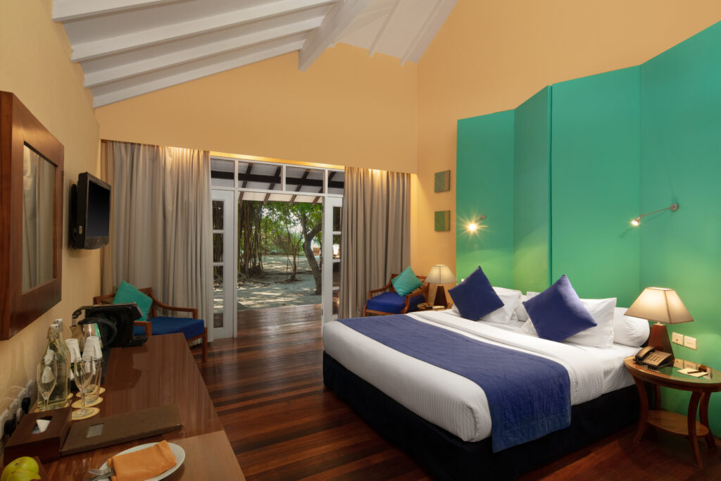 Cozy bedroom interior at Adaaran Meedhupparu with teal and yellow walls
