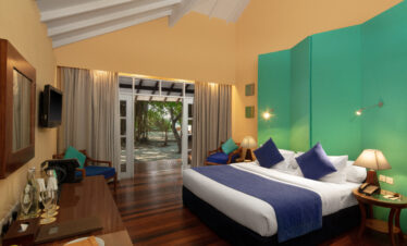 Cozy bedroom interior at Adaaran Meedhupparu with teal and yellow walls