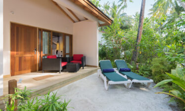 Cozy outdoor patio of a beach villa at Vilamendhoo with lounge chairs and lush tropical plants