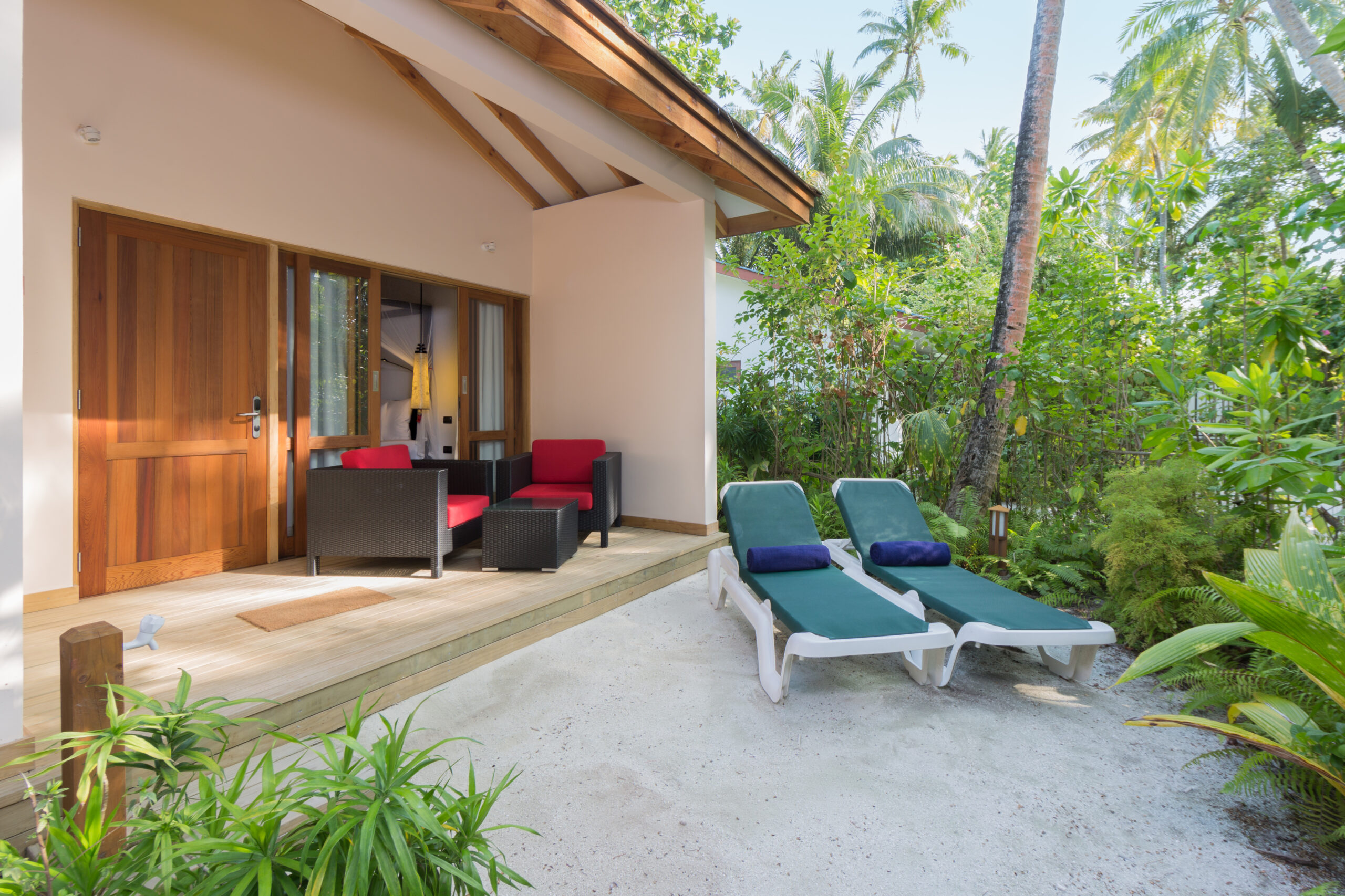 Cozy outdoor patio of a beach villa at Vilamendhoo with lounge chairs and lush tropical plants