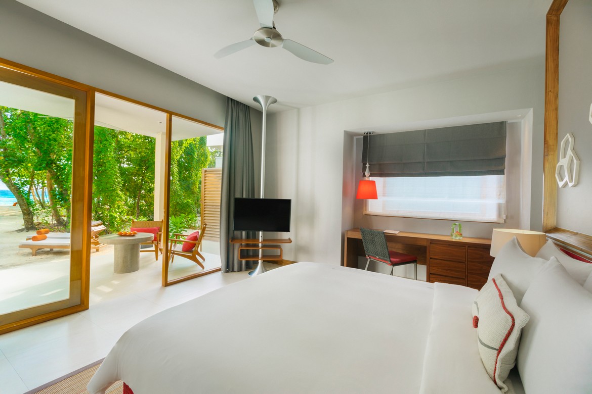 Dhigali resort bedroom with large windows overlooking tropical greenery
