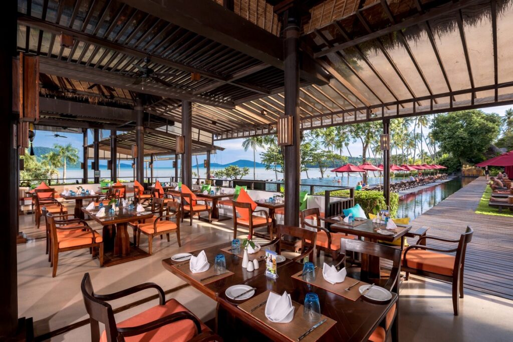 Dining area with ocean view at The Vijitt Resort featuring wooden tables and vibrant cushions