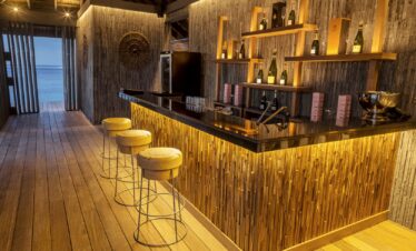 Elegant bar area with stools and dim lighting at Hurawalhi Island Resort