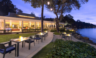 Evening dining setup by the water at Amari Phuket with glowing lights and greenery
