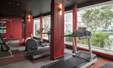 Fitness center at Avani Chaweng Samui featuring treadmills and weightlifting equipment with a view of the outdoors