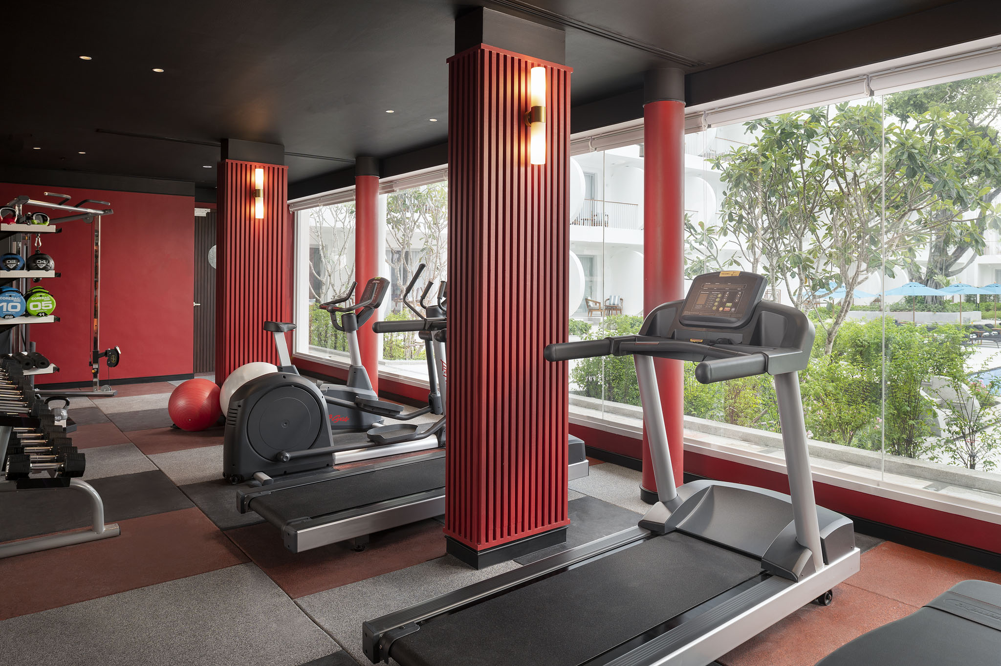 Fitness center at Avani Chaweng Samui featuring treadmills and weightlifting equipment with a view of the outdoors