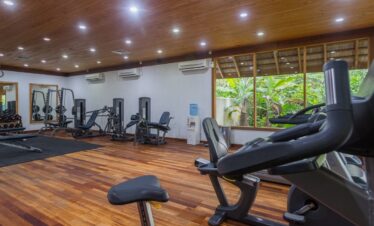 Fully equipped gym at Vilamendhoo with modern exercise machines and a view of the surrounding tropical greenery