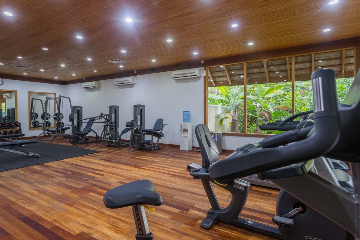 Fully equipped gym at Vilamendhoo with modern exercise machines and a view of the surrounding tropical greenery