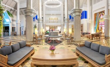 Grand lobby of Chada Thai Village with columns and seating areas beneath a large, ornate chandelier