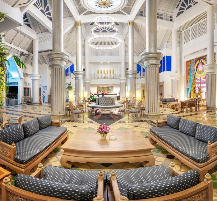 Grand lobby of Chada Thai Village with columns and seating areas beneath a large, ornate chandelier