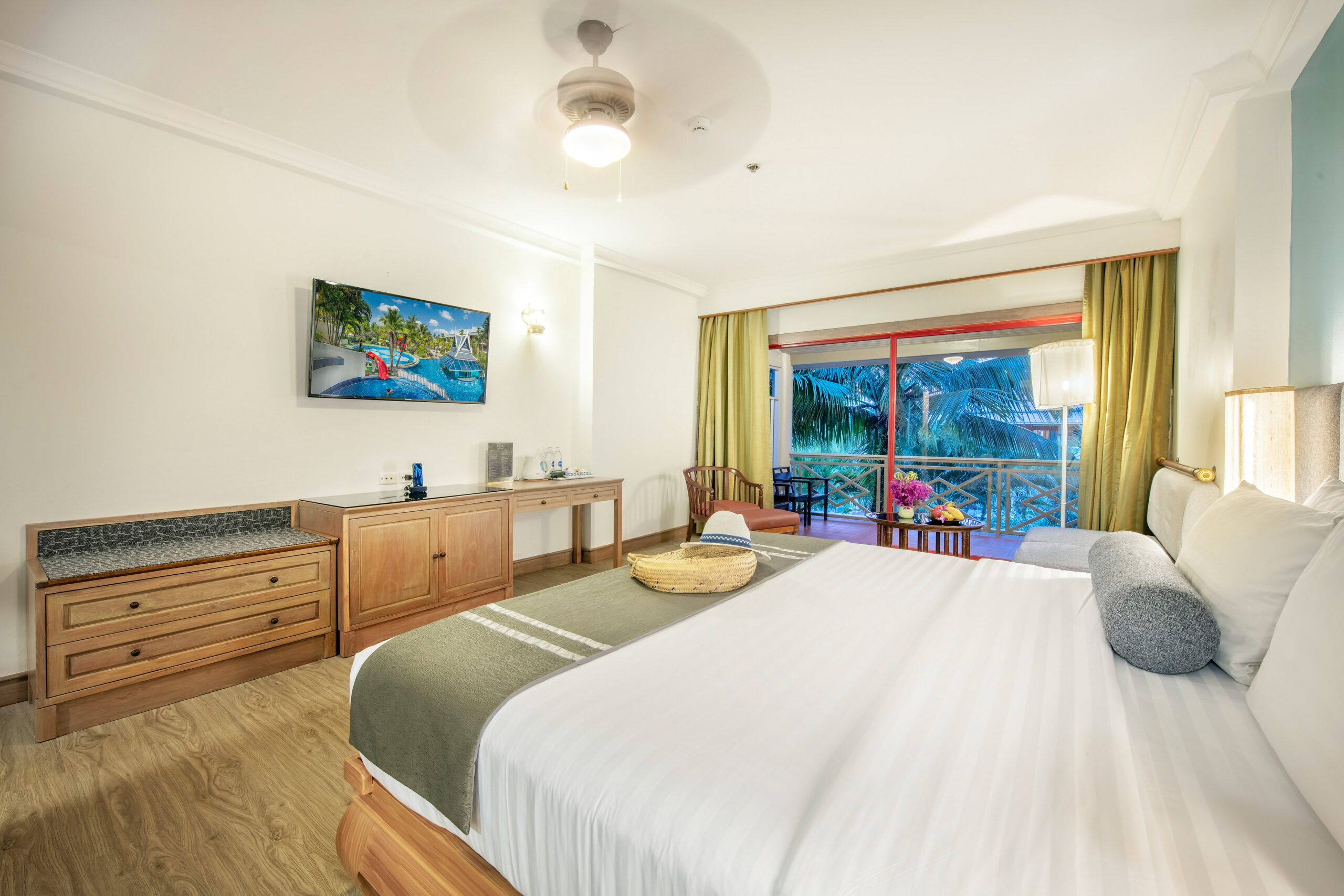 Guest room at Chada Thai Village with a large bed, balcony view, and wooden furniture throughout