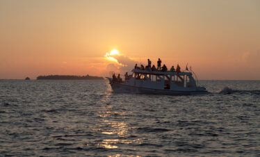 Guests enjoying a sunset cruise from Vilamendhoo as the sun dips below the horizon lighting up the sky