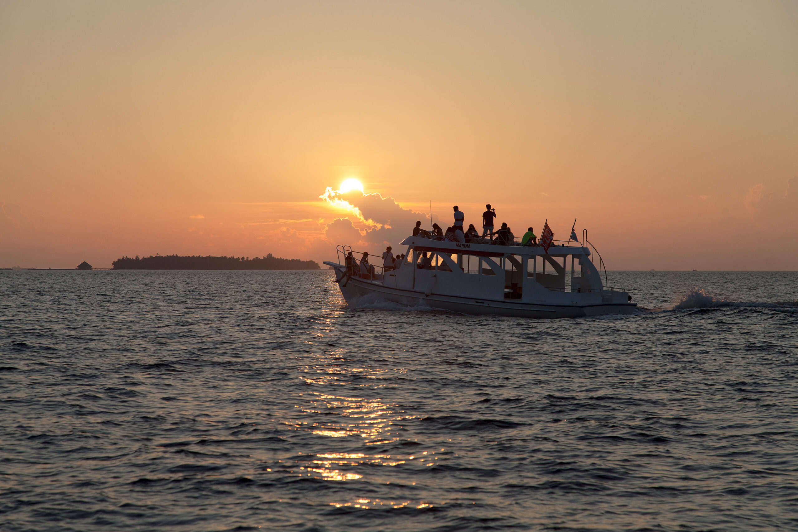 Guests enjoying a sunset cruise from Vilamendhoo as the sun dips below the horizon lighting up the sky