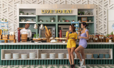 Guests enjoying breakfast at Avani Chaweng Samui restaurant with vibrant decor and live to eat sign