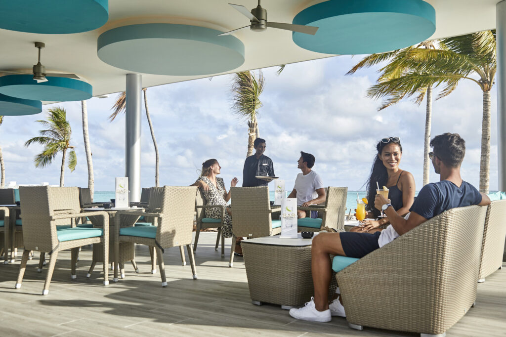 Guests enjoying drinks at an outdoor seating area at Riu Atoll with ocean views