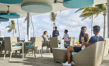 Guests enjoying drinks at an outdoor seating area at Riu Atoll with ocean views